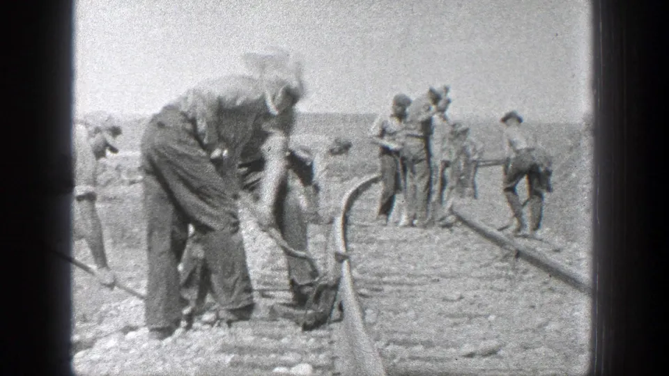 Men appear to maintain a railroad line in 1936 California, with shovels, hats, rails, and gravel visible in a black-and-white 8mm frame.