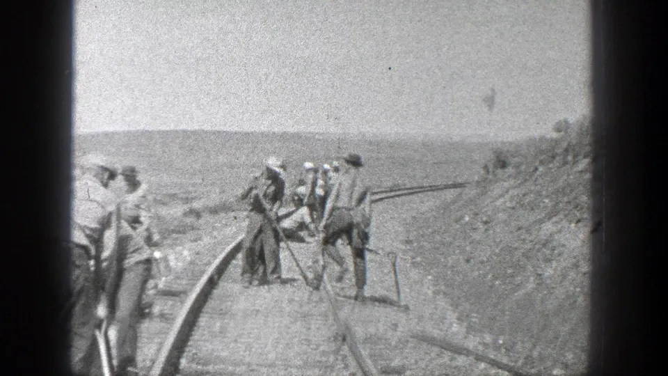 A wider 1936 California view shows men standing and working along curved railroad track across an open rail bed.