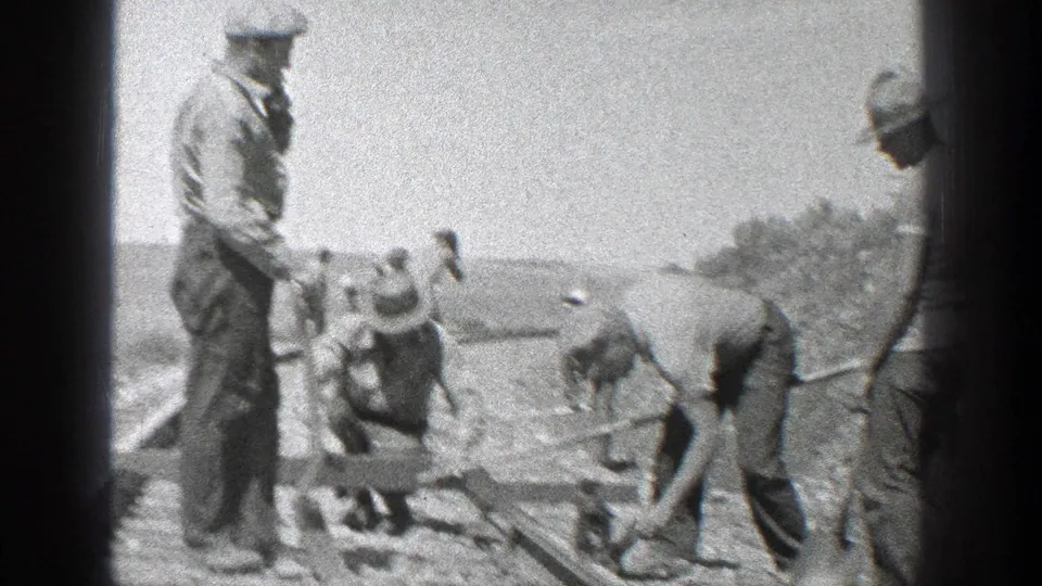 1936 California 8mm frame showing several men in work clothes gathered along railroad tracks with hand tools.