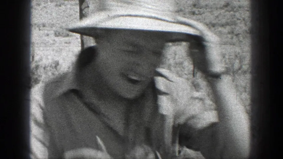 Close view of a man in a light hat and work shirt, likely from the 1936 California home-movie footage, partly obscured by soft focus and film gate edges.