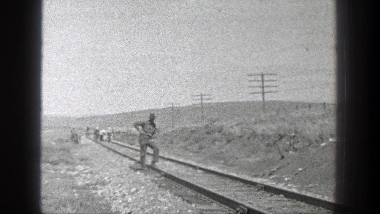 Railroad workers stand and walk along tracks in a dry open landscape.