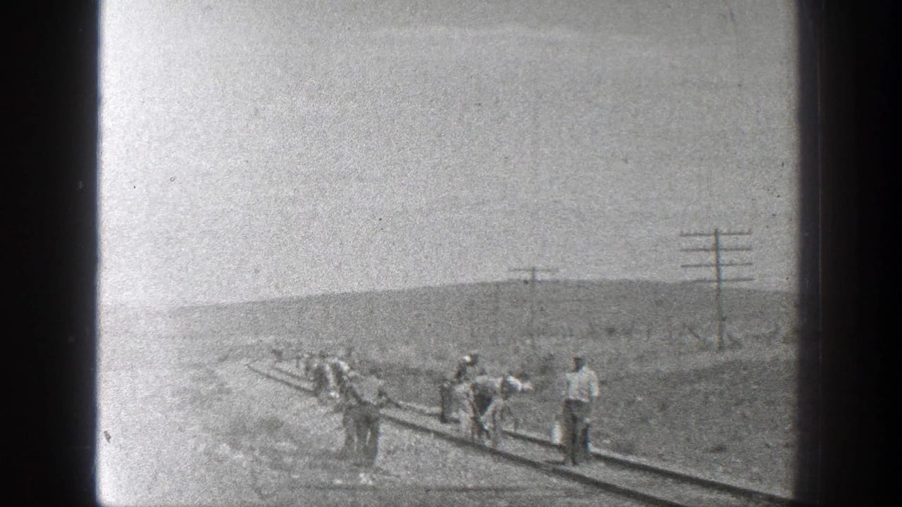 Small group of workers moves along a railway track near utility poles.