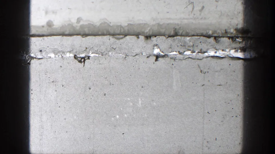 A nearly blank, overexposed 8mm frame shows film wear, frame edge, and only faint traces of the preceding railway landscape.