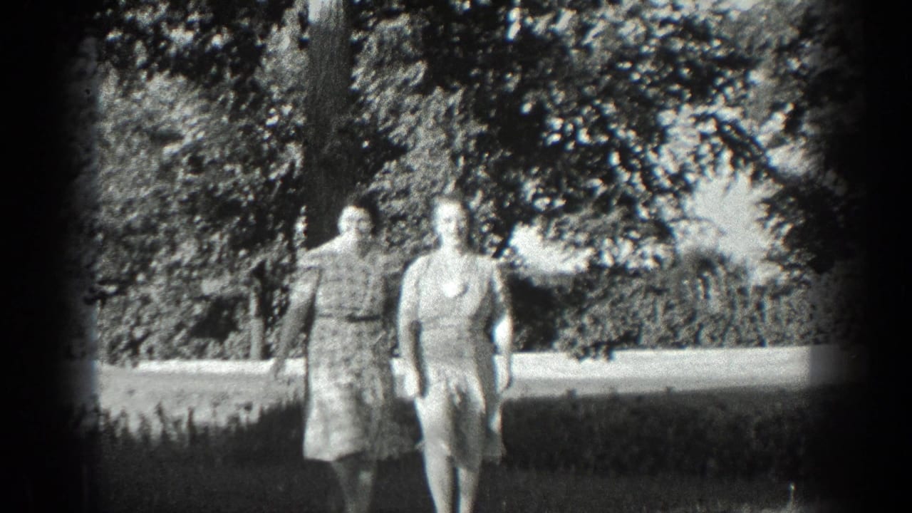 Two adult women in dresses walk along a garden path.
