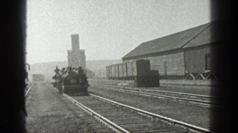 1936 California rail scene showing a small rail vehicle with several men approaching beside freight cars and an industrial building.