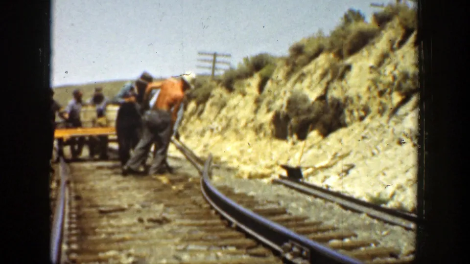 California railway maintenance workers appear beside rails, ties, tools, and a work cart in this 1936 8mm frame.