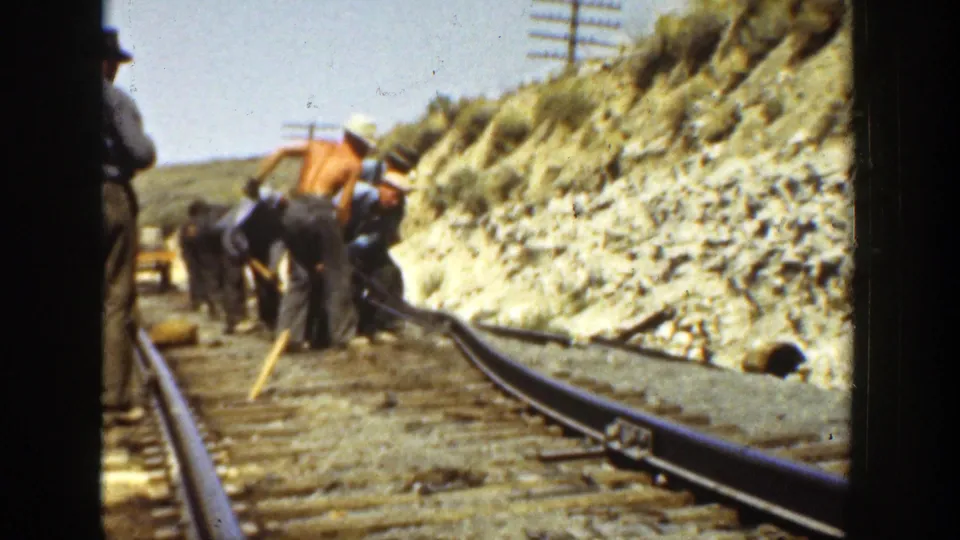 A 1936 California railway work scene shows men pushing or guiding rail by hand, with hillside rock and utility poles in the background.