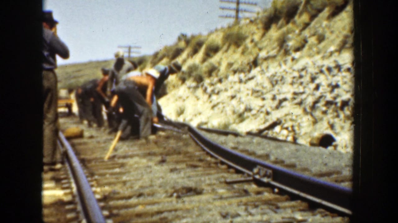 1936 California 8mm frame of workers maintaining a rail line beside a cut hillside, with tracks and utility poles visible.