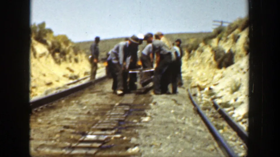 Several railway workers appear to handle equipment on narrow rails, filmed from a handheld 8mm viewpoint in 1936 California.