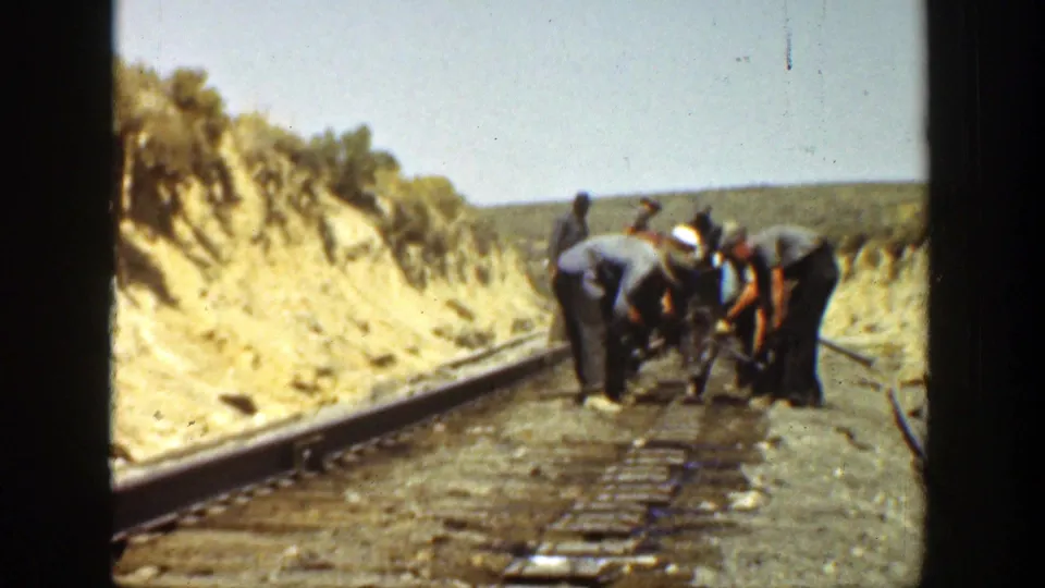 At the end of the clip, workers remain grouped on the railway tracks in a dry California landscape, partly obscured by film softness.