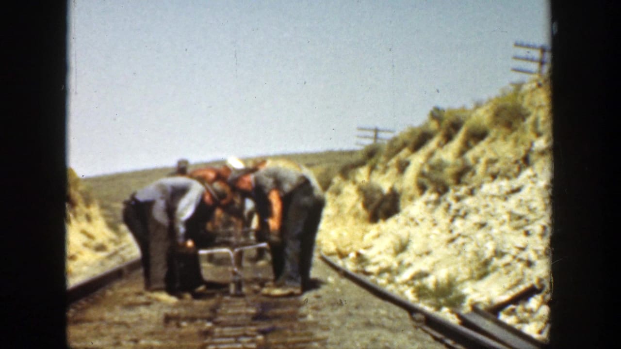 A group of workers cluster around track hardware on a railway line.