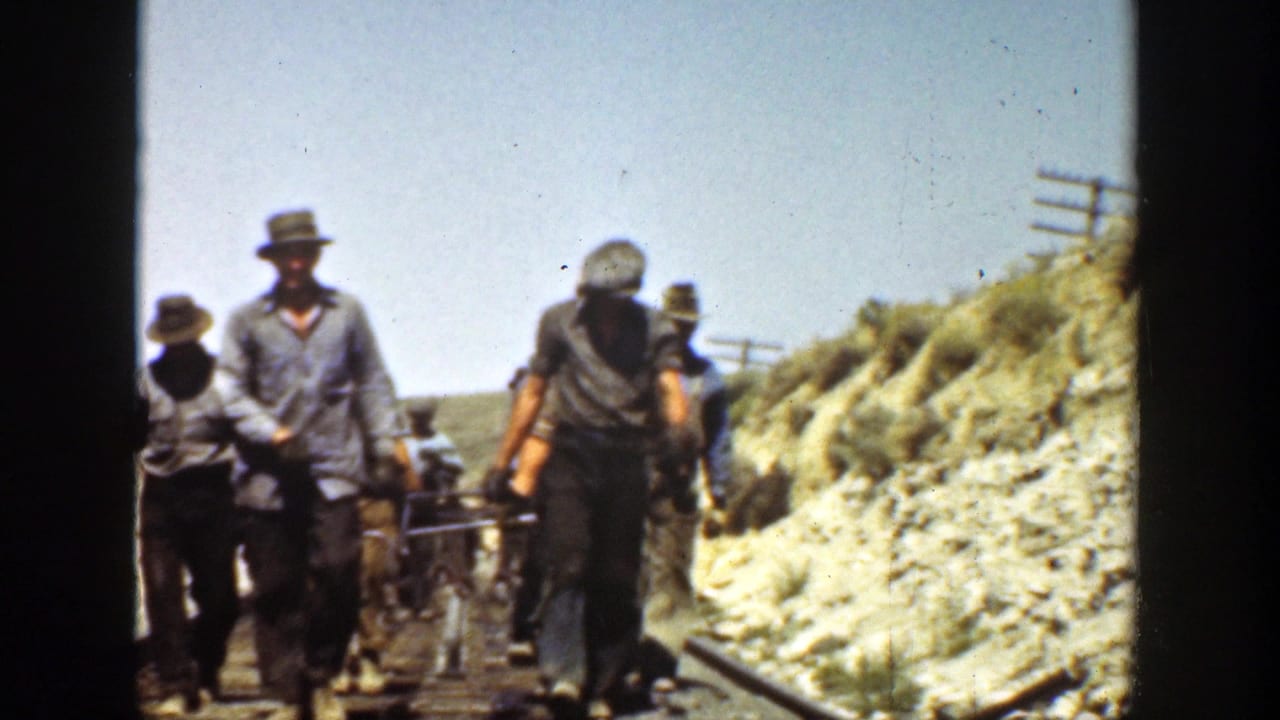 California 1936 8mm frame showing workers on or beside a railroad track in a dry landscape, with tools and rails visible.