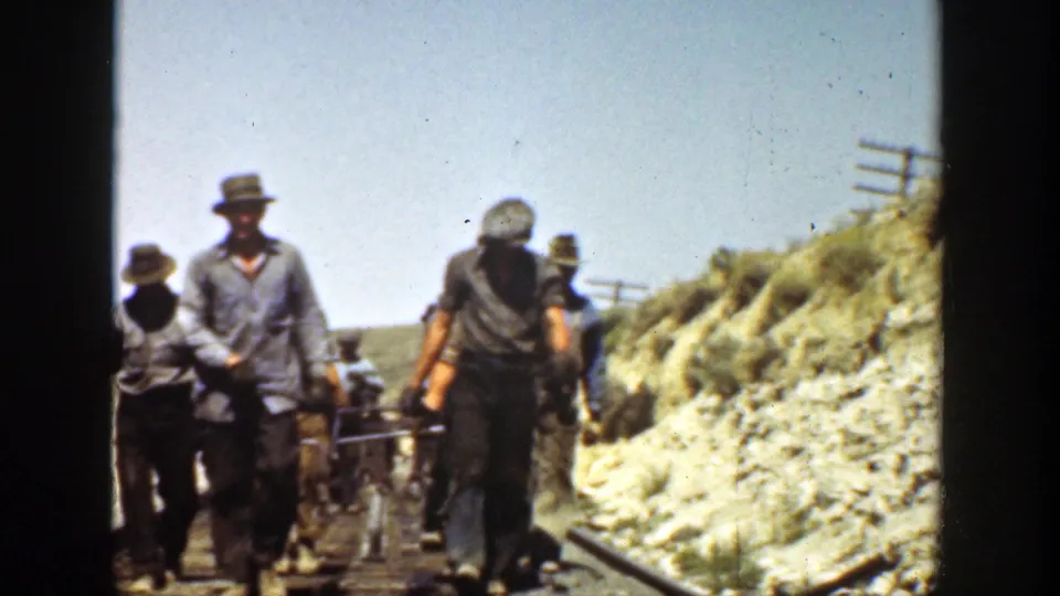 California 1936 8mm frame showing workers on or beside a railroad track in a dry landscape, with tools and rails visible.