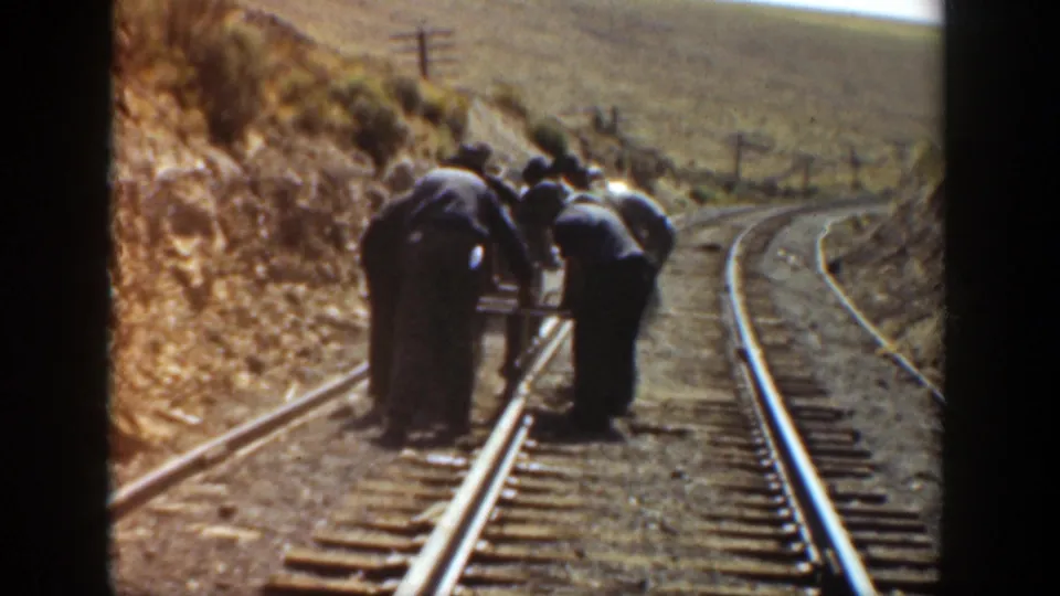 1936 California footage appears to show workers gathered on railroad tracks, bending near the rails in a dry hillside setting.