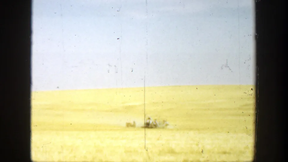 1936 California home-movie frame with a small distant group crossing or standing in an open field under bright daylight.