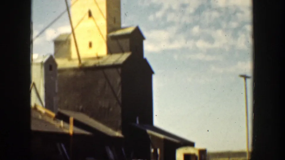 1936 California 8mm frame showing a large yellow-and-black industrial grain elevator with dark lower buildings and open sky.