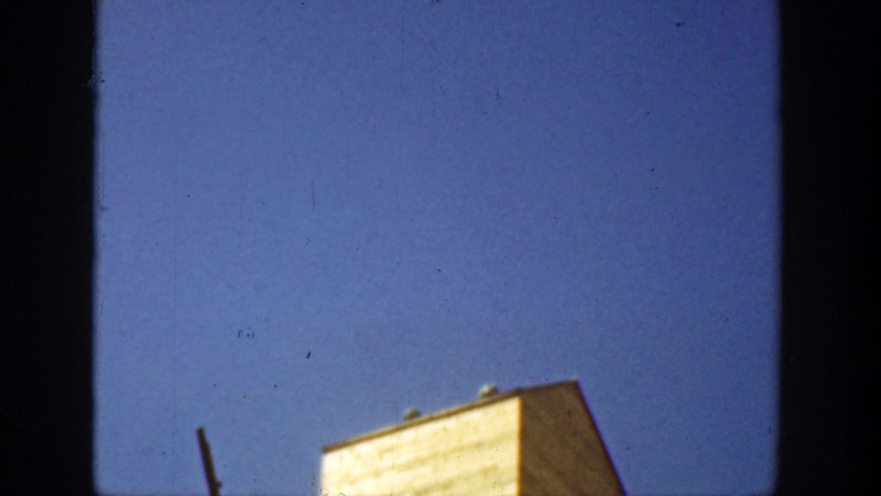 1936 California 8mm frame showing the upper portion of a pale tower against deep blue sky, with visible film gate edges.