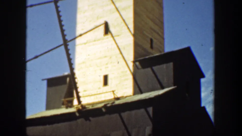 Final 1936 California frame showing a pale tower behind a darker adjacent roofline, with a ladder-like foreground structure.