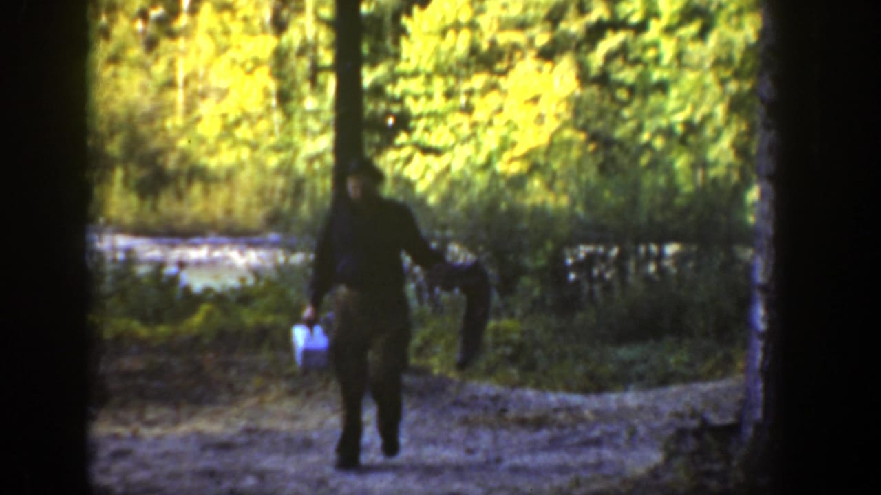 Man walking on a wooded path carrying a small blue and white case.
