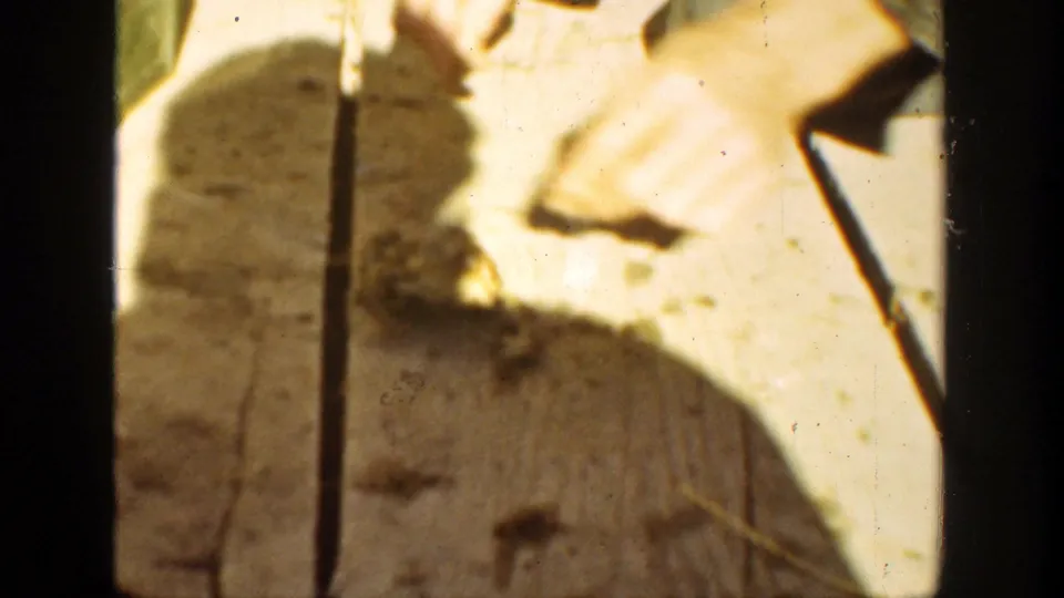 The final frame shows a dark shadow over a sunlit wooden surface, with a thin vertical strap and pale objects near the edge of view.
