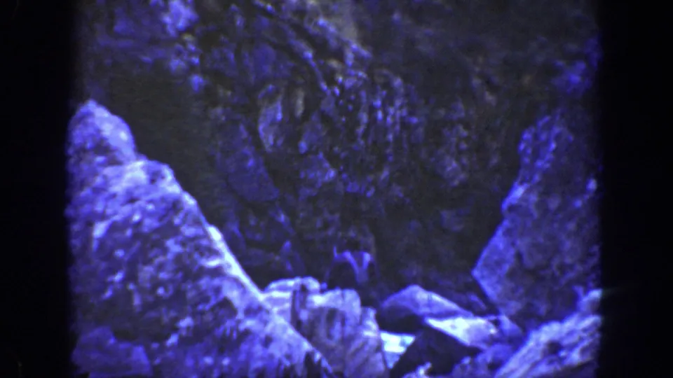 Blue-tinted 8mm frame of a rocky California canyon area, with large stone forms and no clearly visible people in this still.