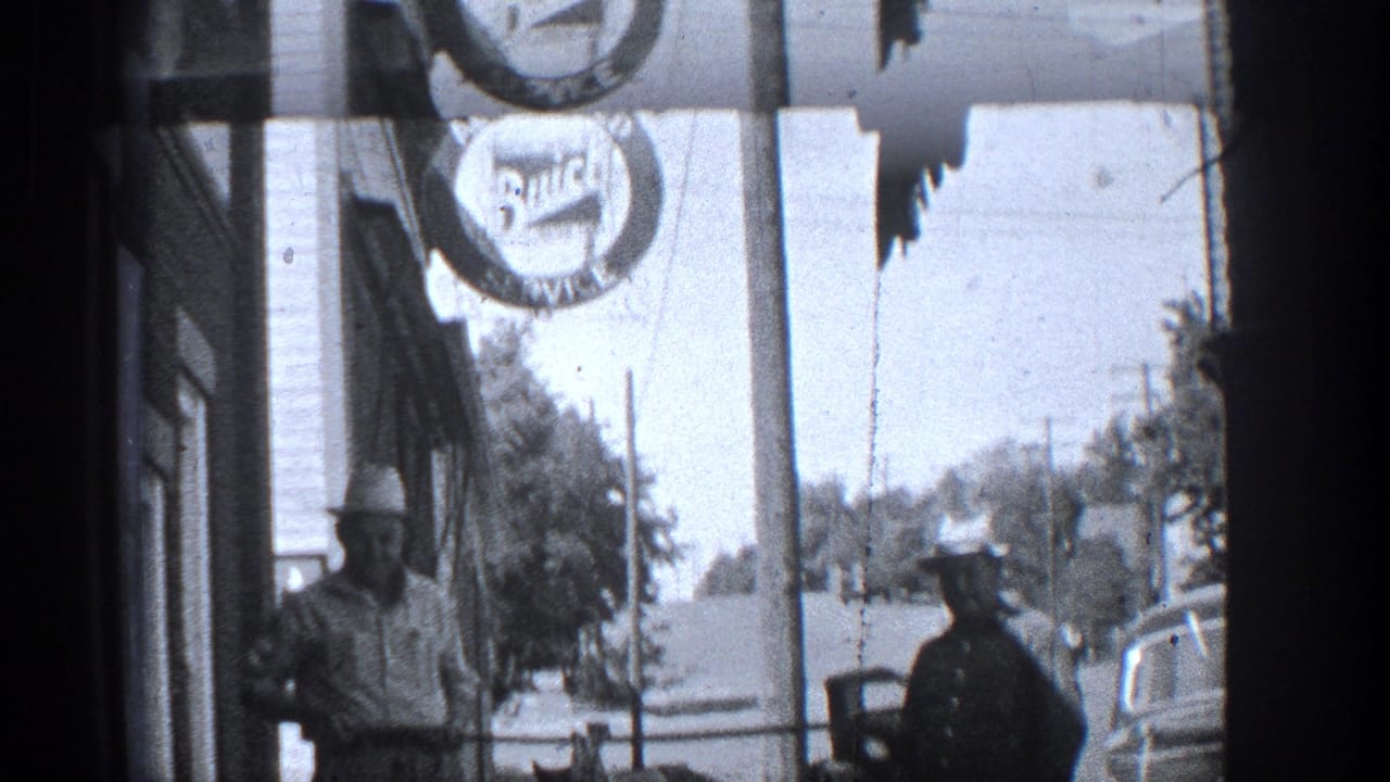 Sidewalk view with a man holding a large fish, a uniformed officer, cars, and a hanging sign overhead.