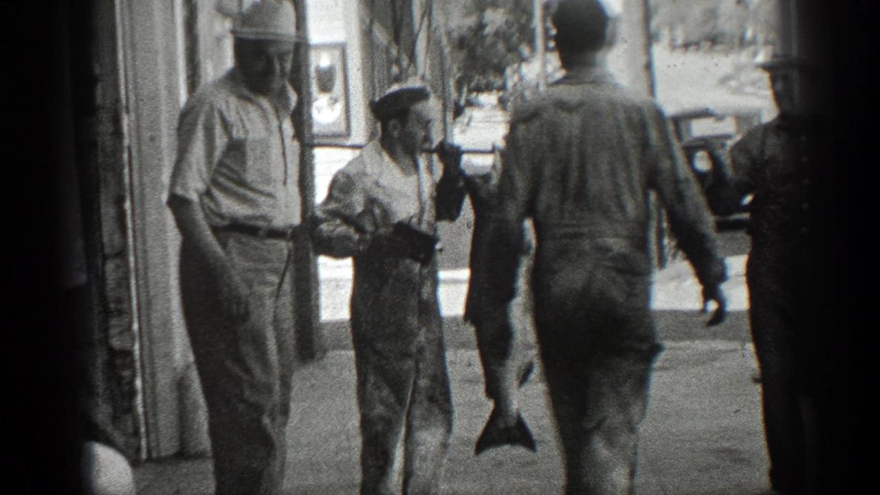 In 1936 California home-movie footage, adult men stand outside a storefront while a large fish hangs from a pole.