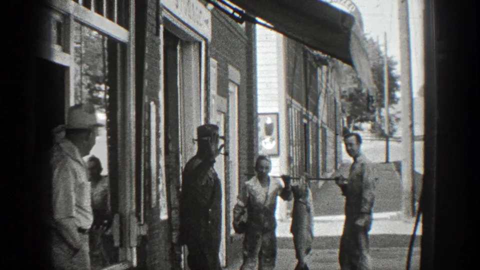 Wider 1936 California street view showing men outside shop windows with a large fish displayed in the foreground.