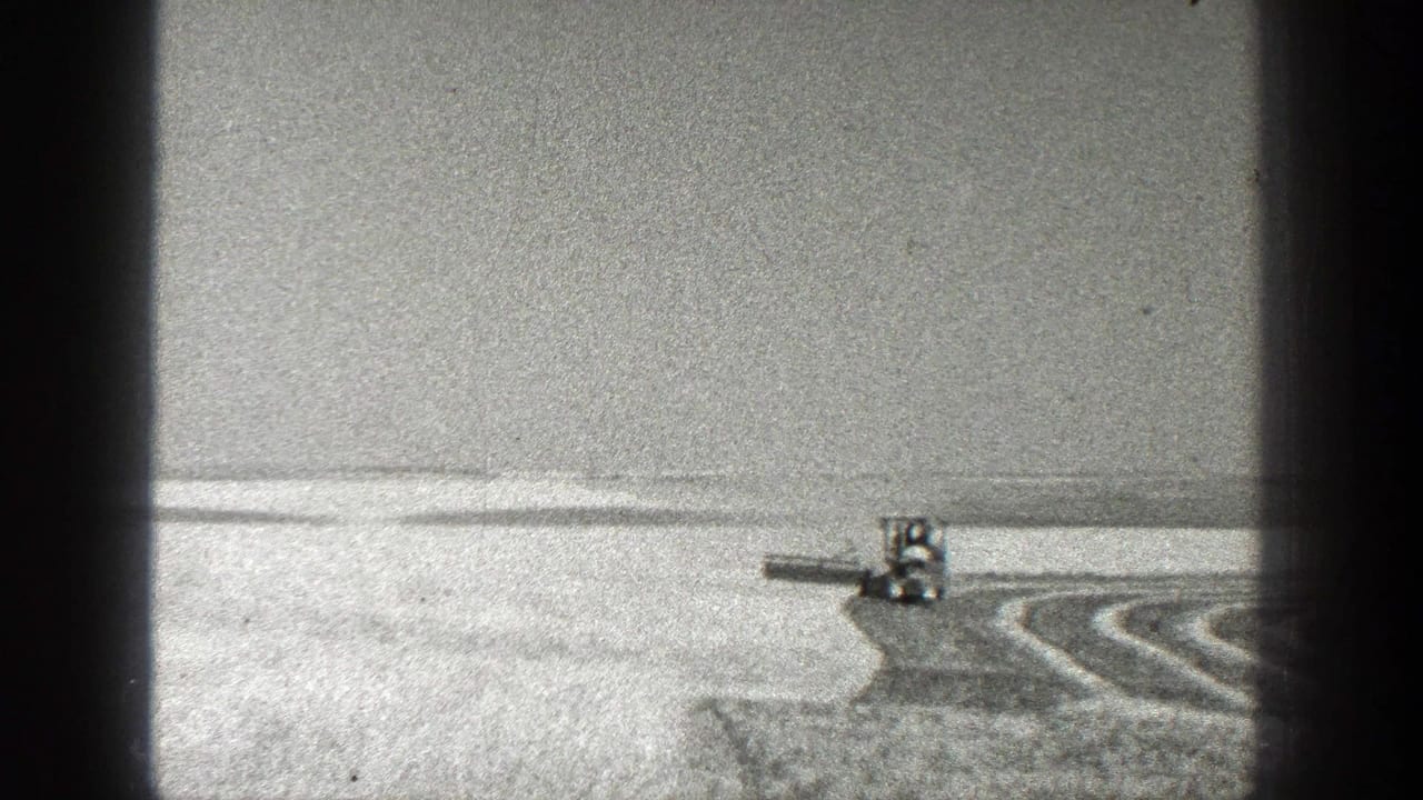 Tractor pulling a field implement across a broad open field with curved rows.