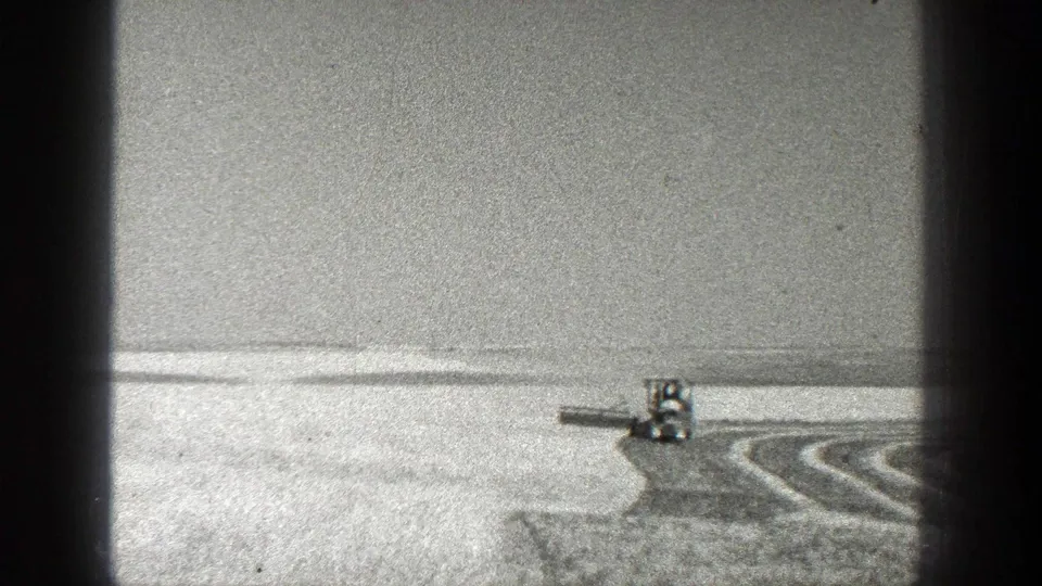 A tractor works across a wide California field, pulling an implement near curved rows visible in the soil or crop pattern.