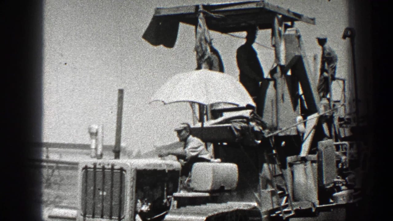 1936 California farm footage showing workers on top of a tractor or agricultural machine, with one man seated under a white umbrella.