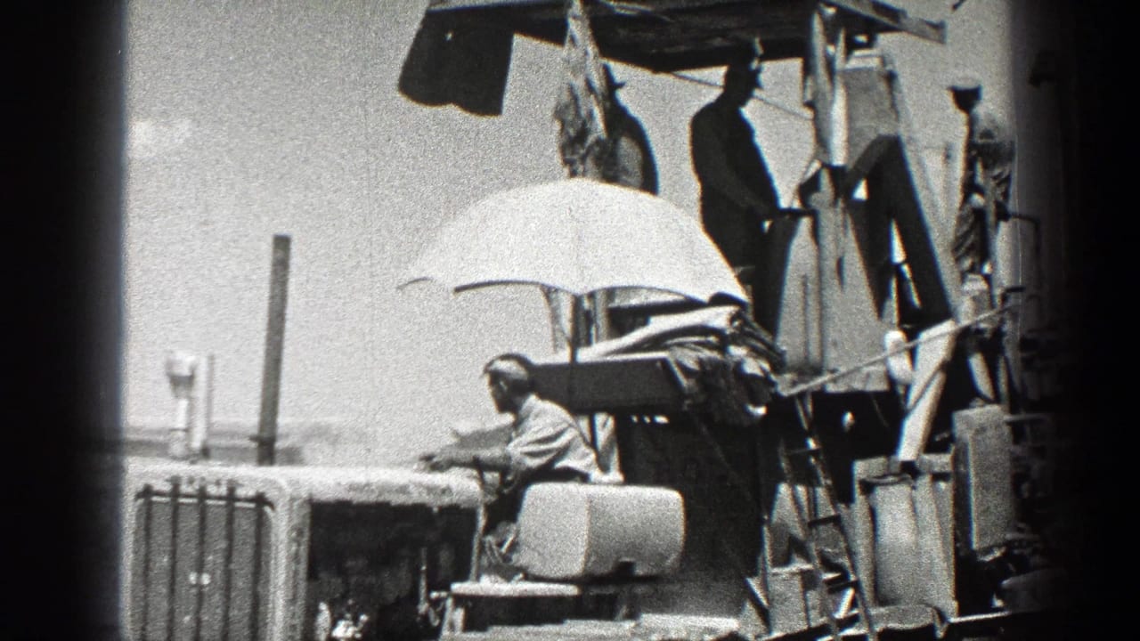 A seated worker and several standing workers are positioned on farm machinery.