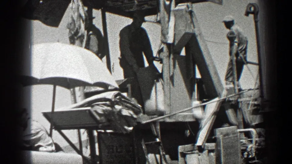 1936 California 8mm frame showing men in work clothes near oil-rig platform structure and machinery.