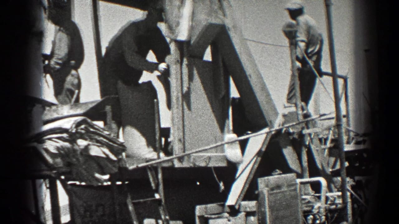 Workers stand on and around a rig platform with machinery below.