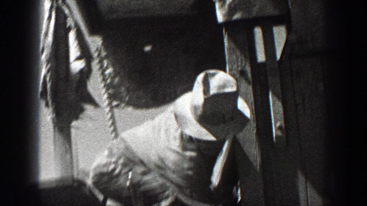 Close view of a man in a hat beside heavy farm equipment.