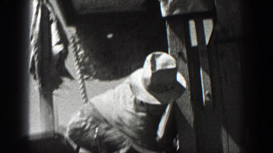 1936 California 8mm frame showing a man in work clothes and hat near the side of a heavy agricultural machine.