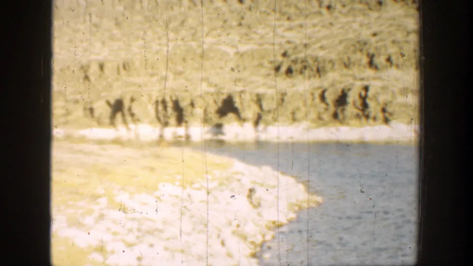 1936 California 8mm frame showing lake water, pale banks, a dark bear-like figure near trees, and heavy window-frame division.