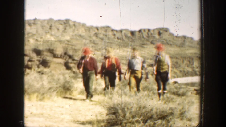Hunters walk through scrubland in a rugged California landscape, seen in soft 1936 8mm home-movie footage.