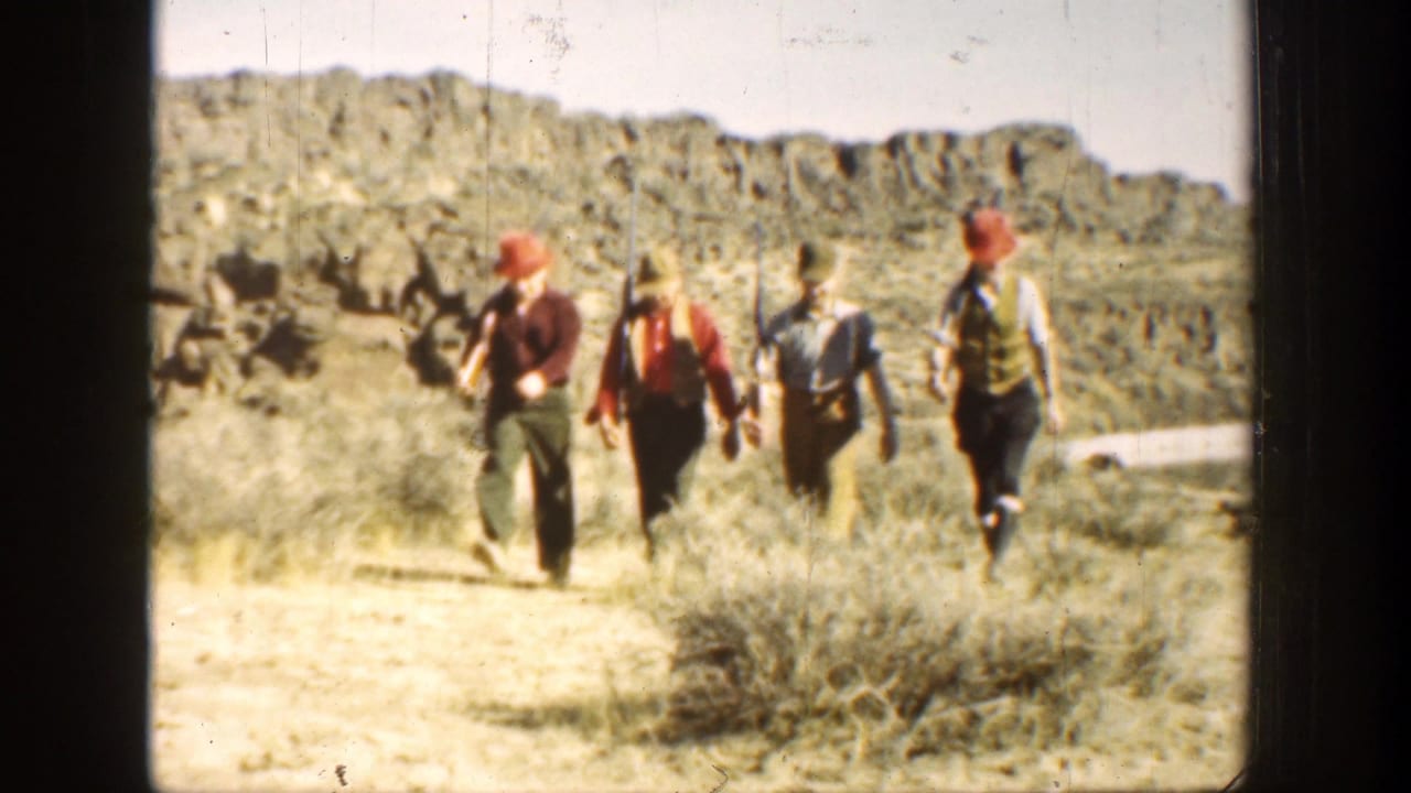 In 1936 California 8mm footage, four men in caps and vests carry rifles while walking toward the camera on a sunlit dirt road.