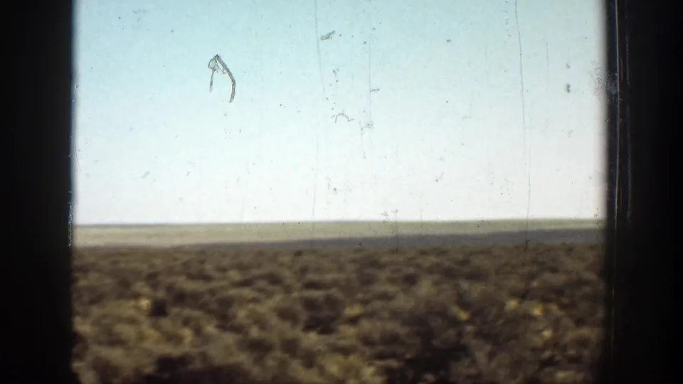 1936 California 8mm view of a broad arid plain, pale sky, and dark framing from a window or film gate.