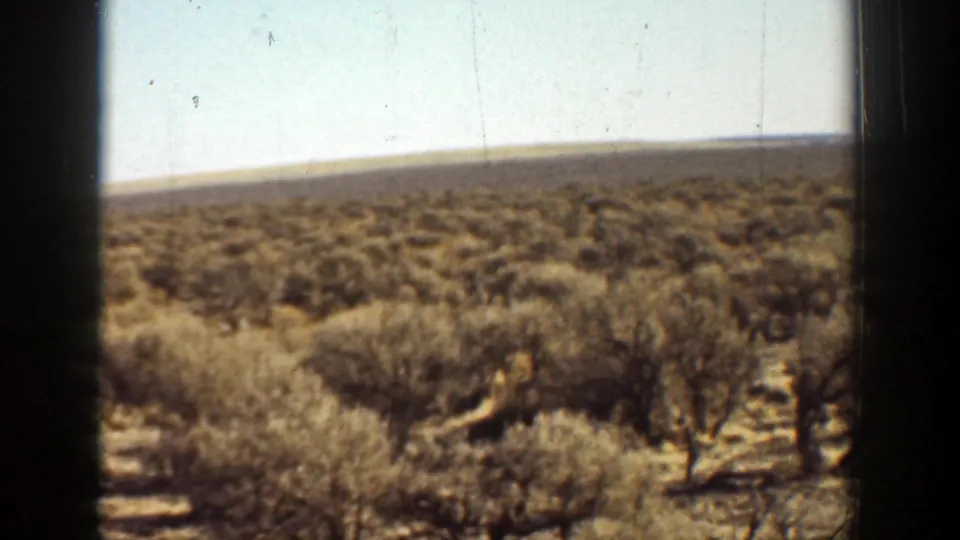 1936 California 8mm frame showing dry scrubland, a pale sky, low hills, and soft home-movie color.