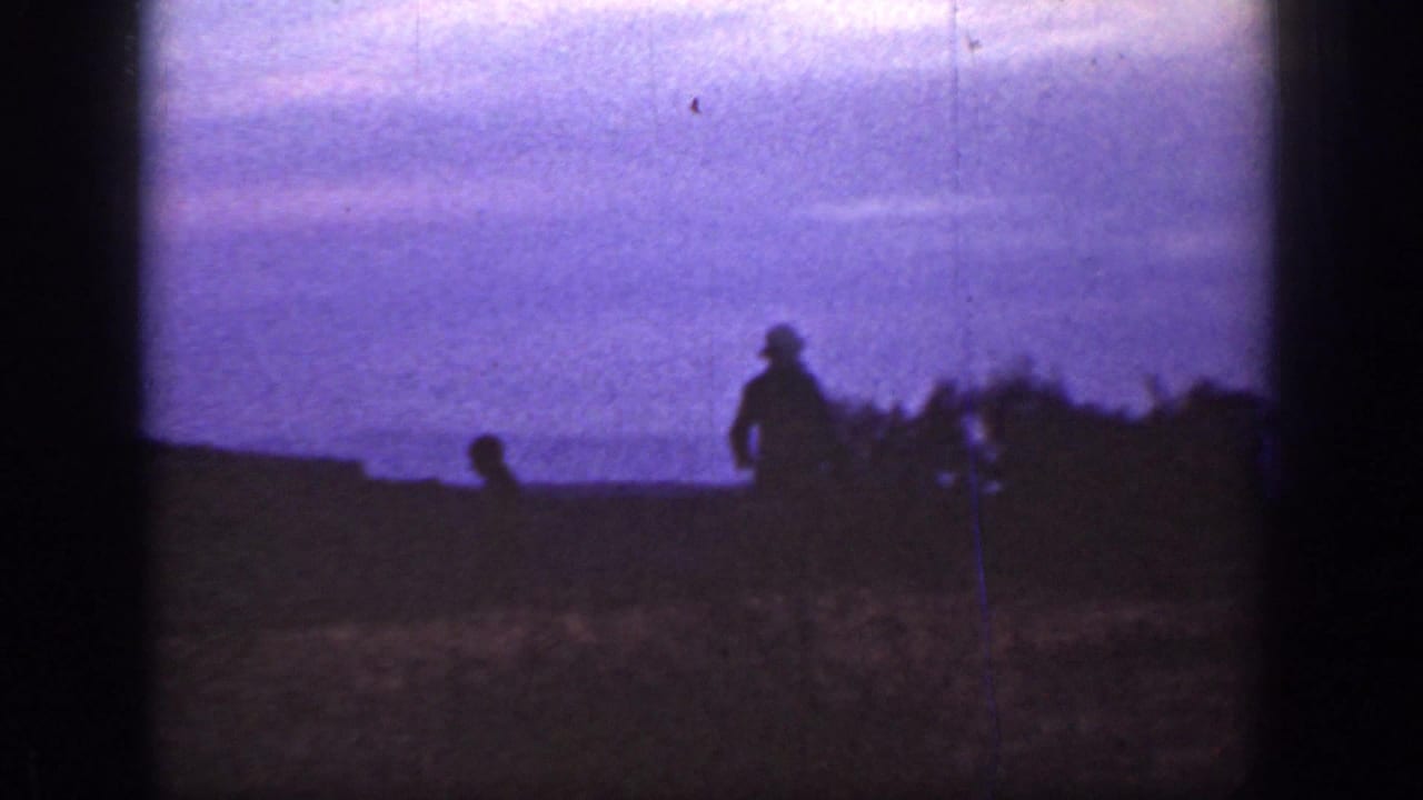 1936 California 8mm frame showing a distant silhouetted figure in a hat on a hillside against a purple dusk sky.