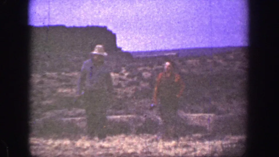 Two adult men in 1936 California home-movie footage walk toward the camera across dry, rocky terrain.