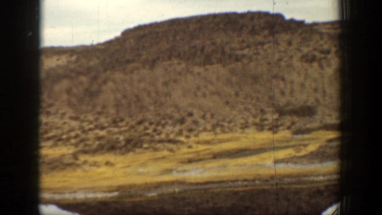 Rocky hillside and dry ground beside a narrow water edge.