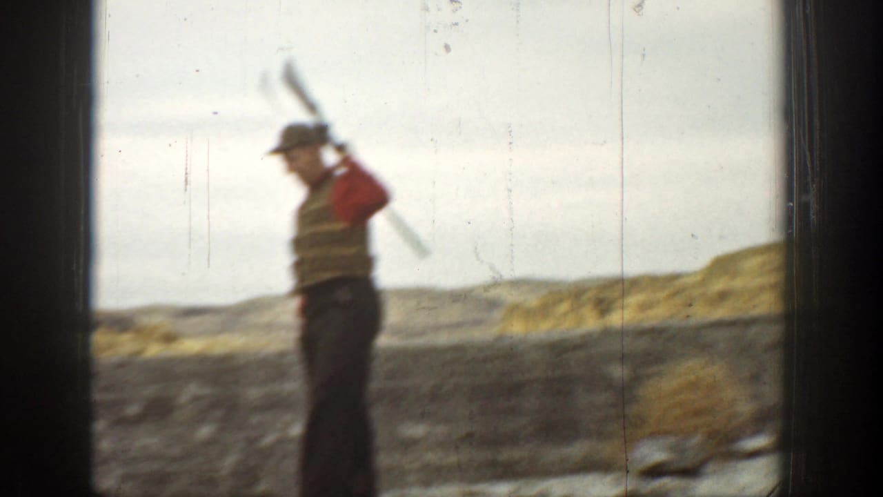 In 1936 California home-movie footage, a man in a red vest and cap stands with a long gun over his shoulder in an arid landscape.