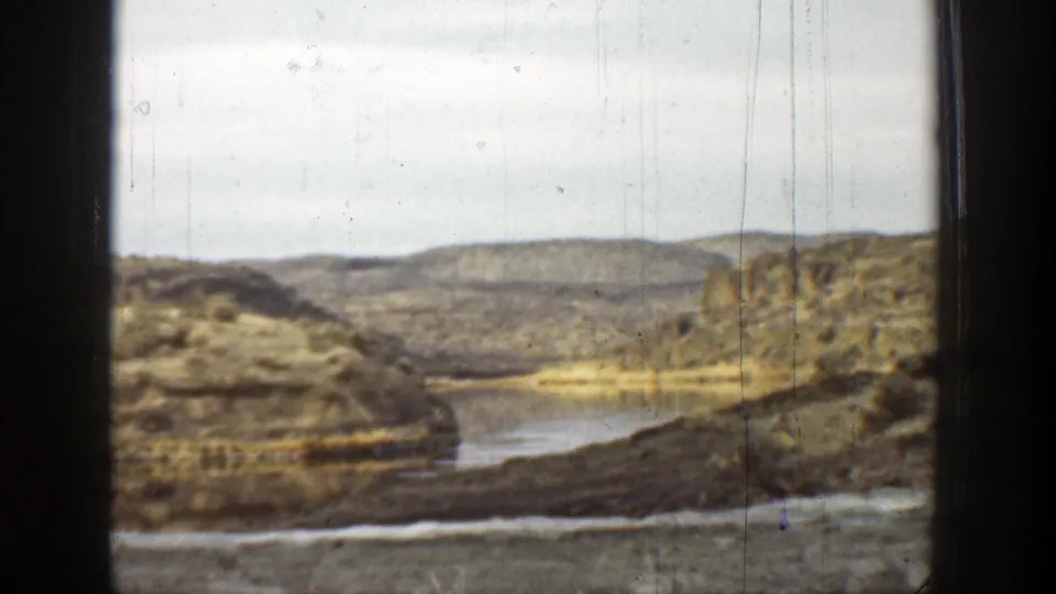 1936 California canyon view with scrub slopes, pale sky, and a narrow watercourse visible through aged 8mm film framing.