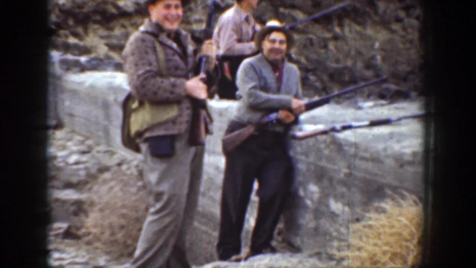 1936 California outdoor frame showing men posed near rocks, with rifles and field bags visible.