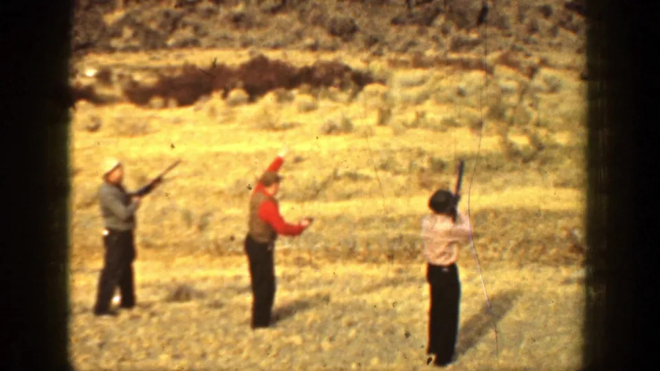 1936 California 8mm frame showing three adults in period clothing holding or raising rifles on an arid plain.
