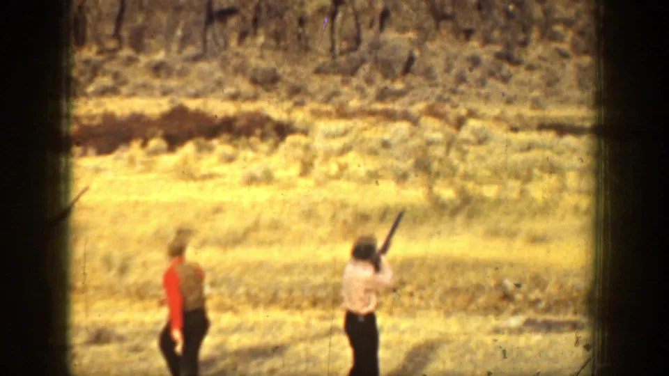 A 1936 California frame shows one man walking across a dry field while another holds a shotgun raised during skeet practice.