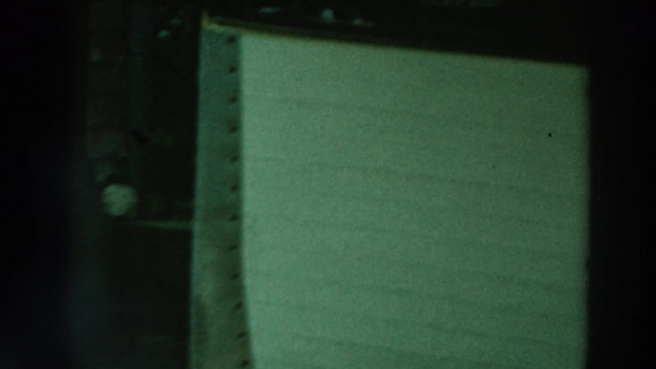 Dark vertical framing beside a pale green wall or panel near a waterfront structure.